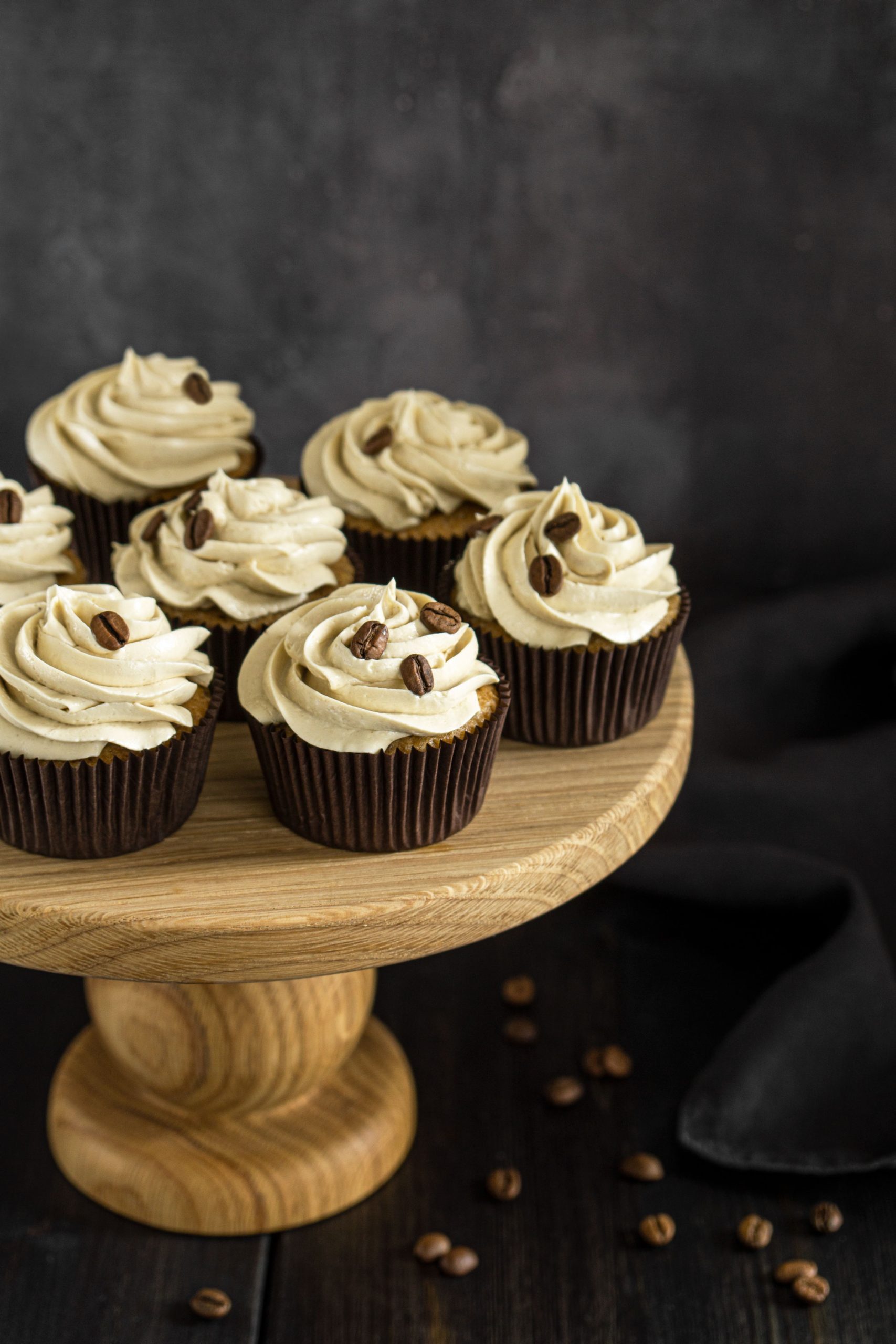 Coffee cupcakes decorated with buttercream and served on a wooden cake stand