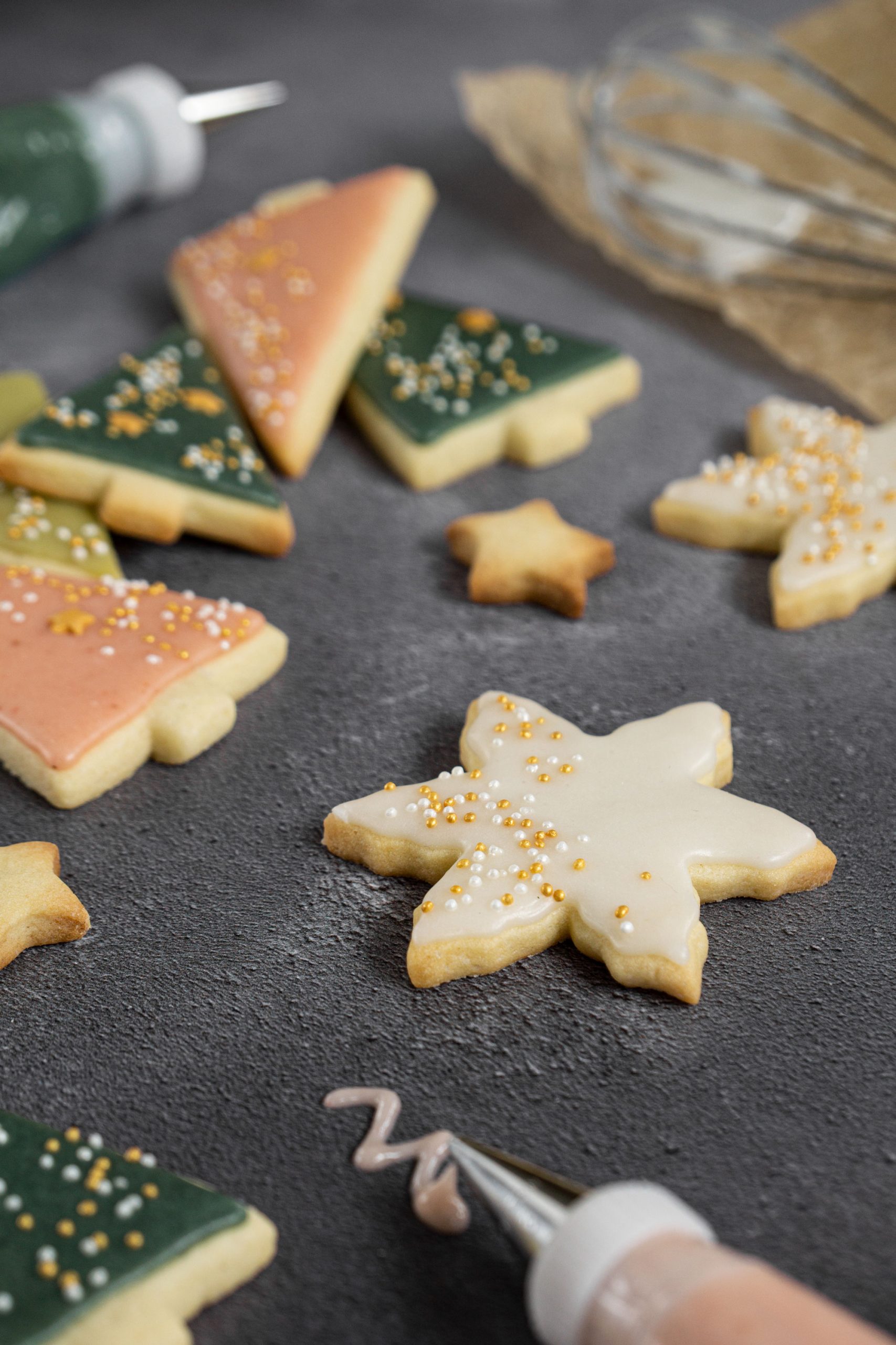 Close up of snowflake shaped sugar cookie decorated with easy cookie icing and gold sprinkles