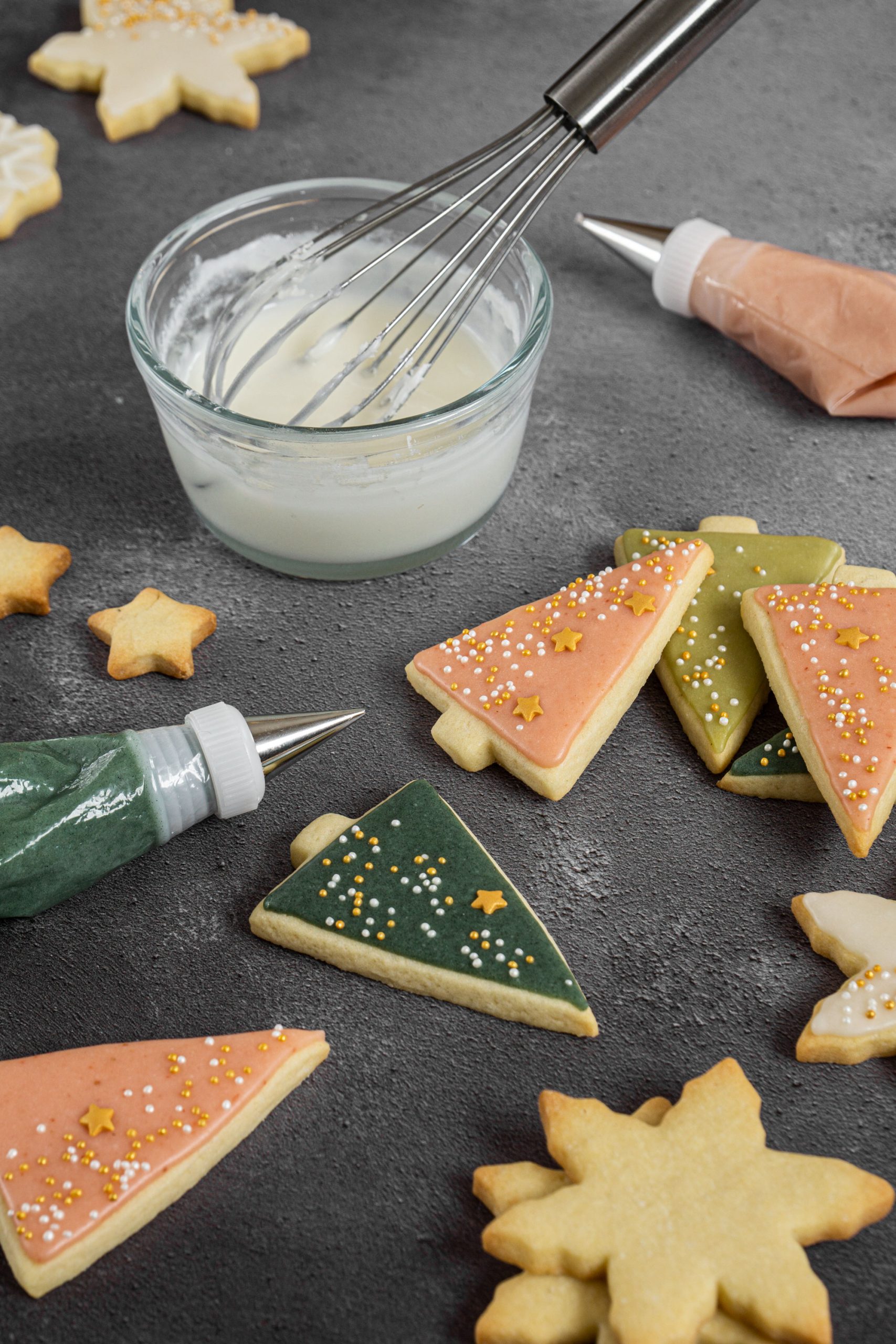 Fir tree shaped sugar cookies decorated with colorful cookie icing and gold sprinkles