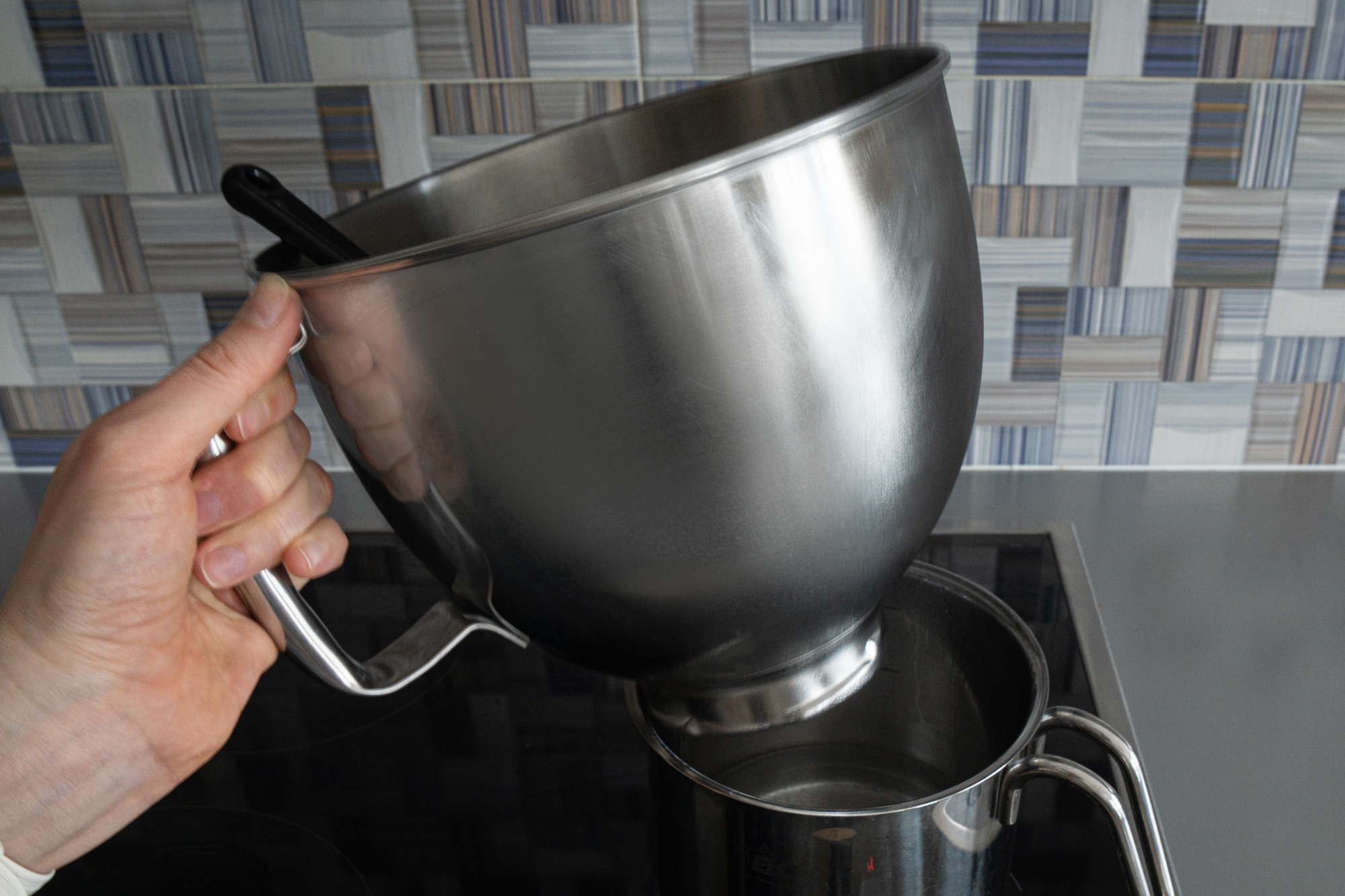 Putting a metal a bowl on a top of a saucepan with steaming water