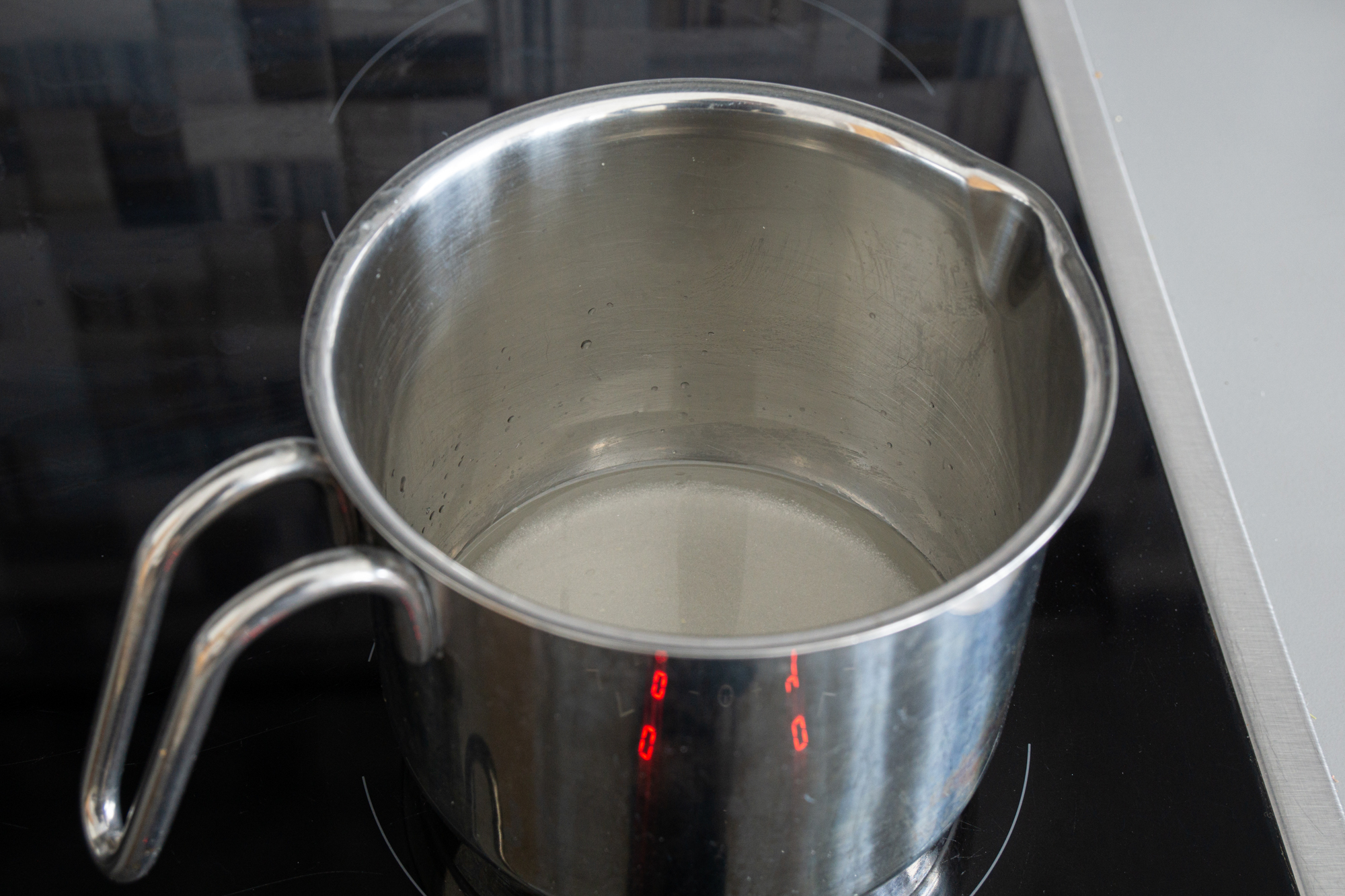 Slowly heating sugar syrup in a saucepan, till the sugar dissolves