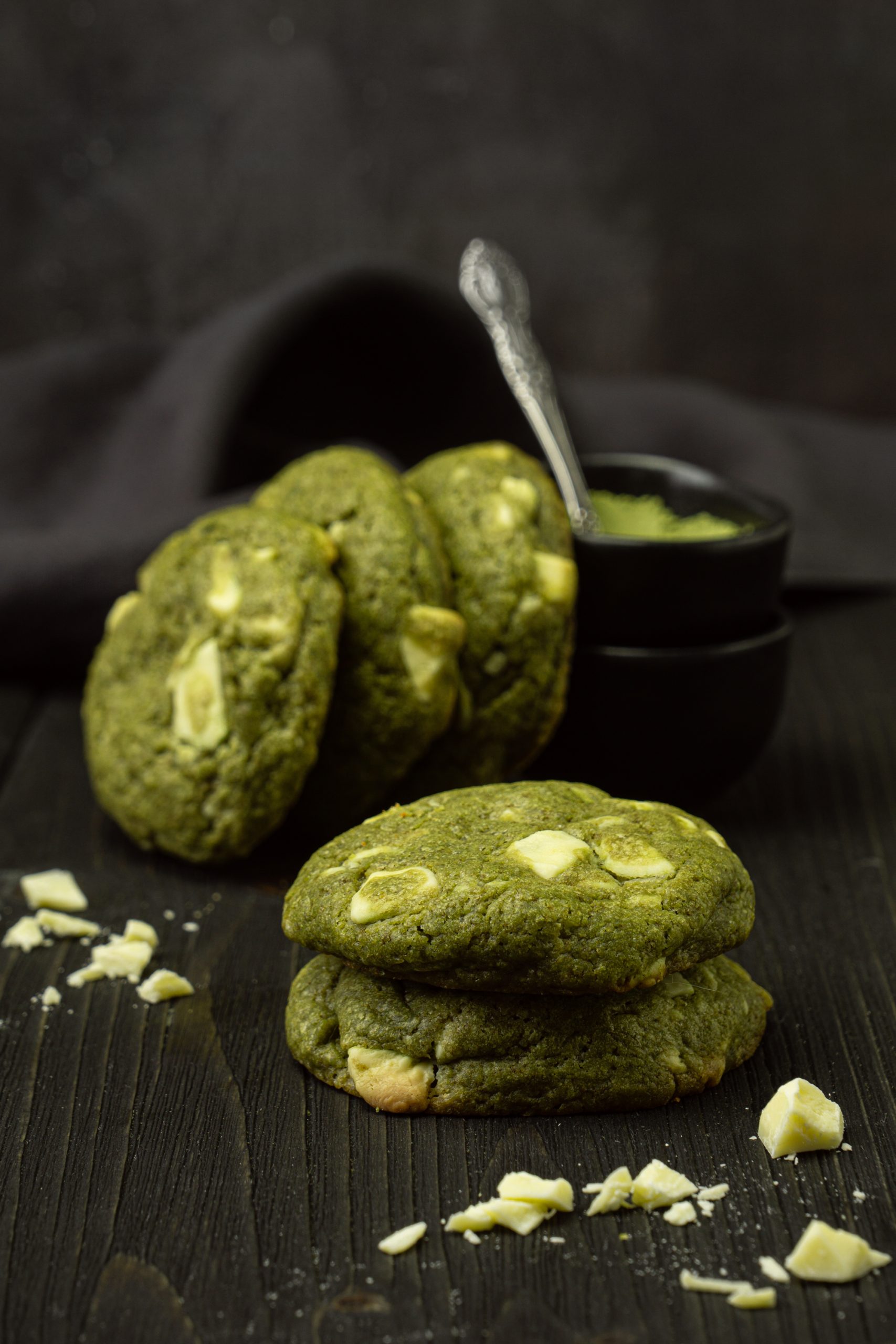Matcha white chocolate chip cookies stacked on a dark background
