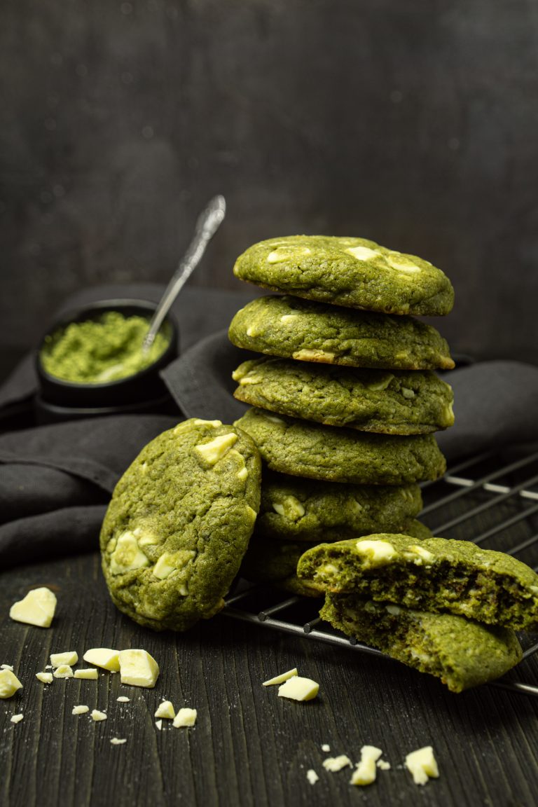 Matcha white chocolate chip cookies stacked on a dark background
