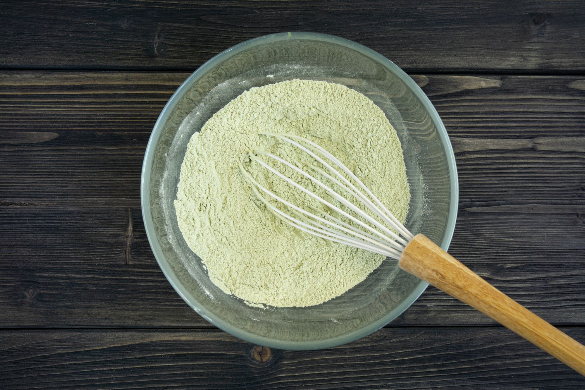 Flour mixed with matcha powder in a glass bowl