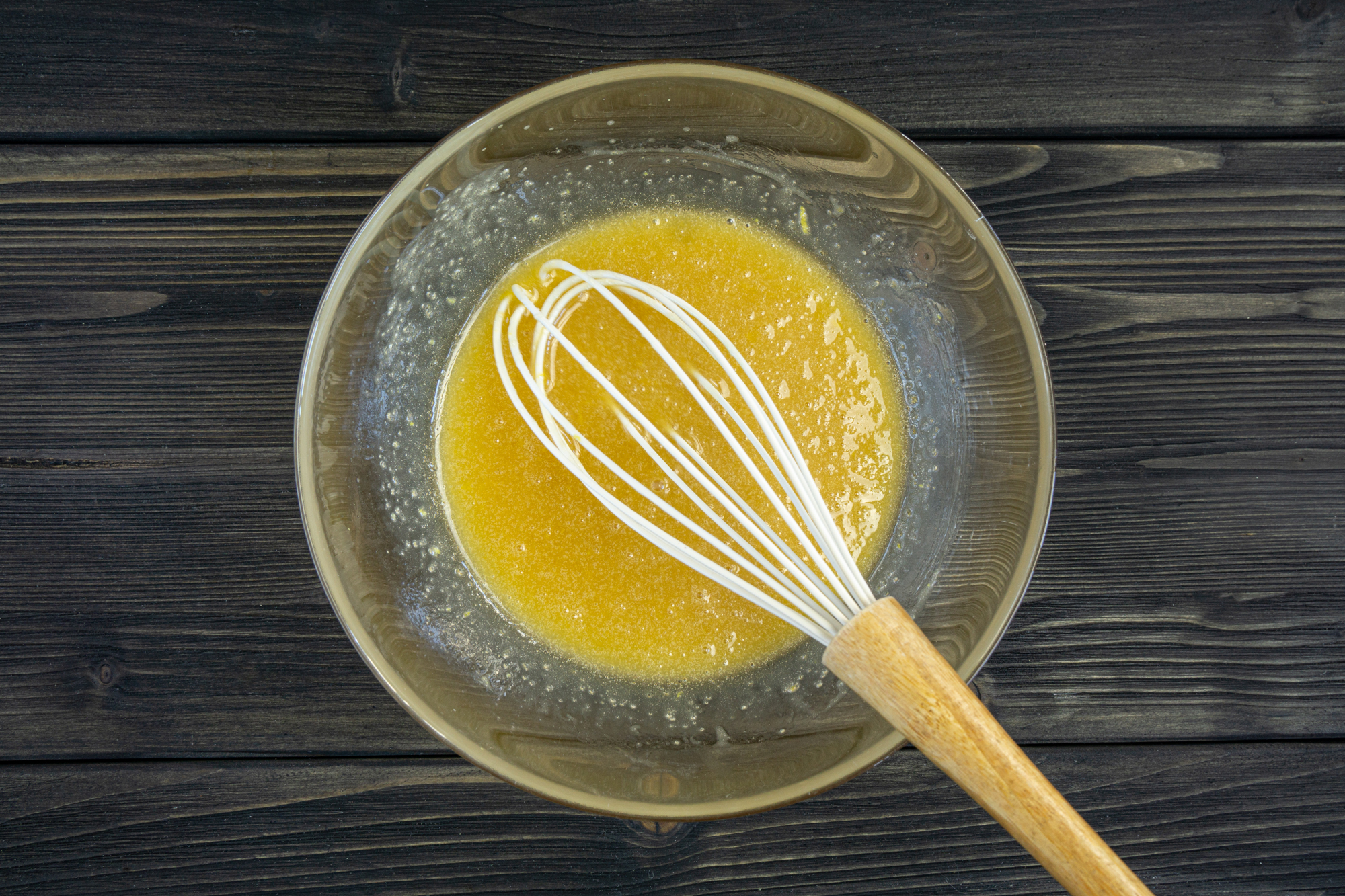 Melted butter mixed with sugar and an egg in a glass bowl