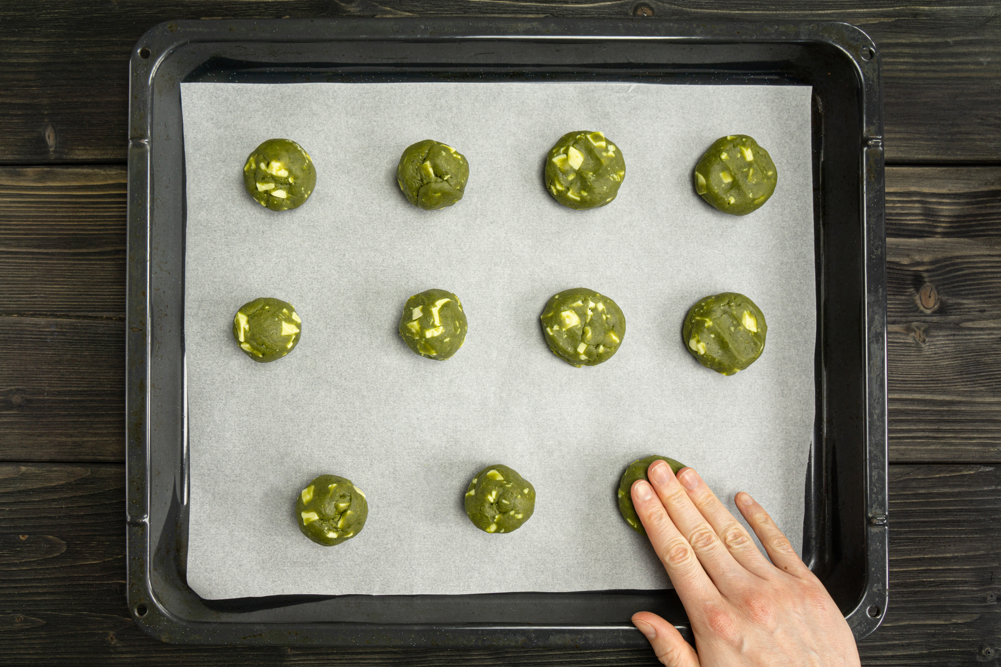 Matcha white chocolate chip cookie dough rolls on a baking sheet