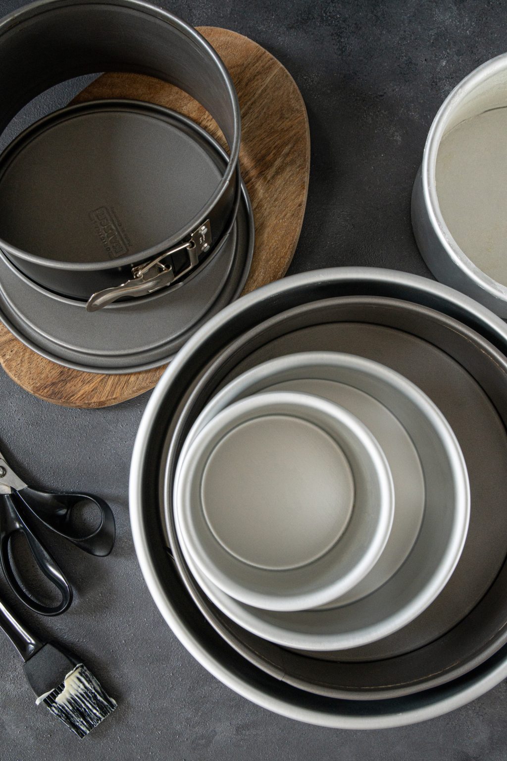 Top view of various cake pans piled on a dark background