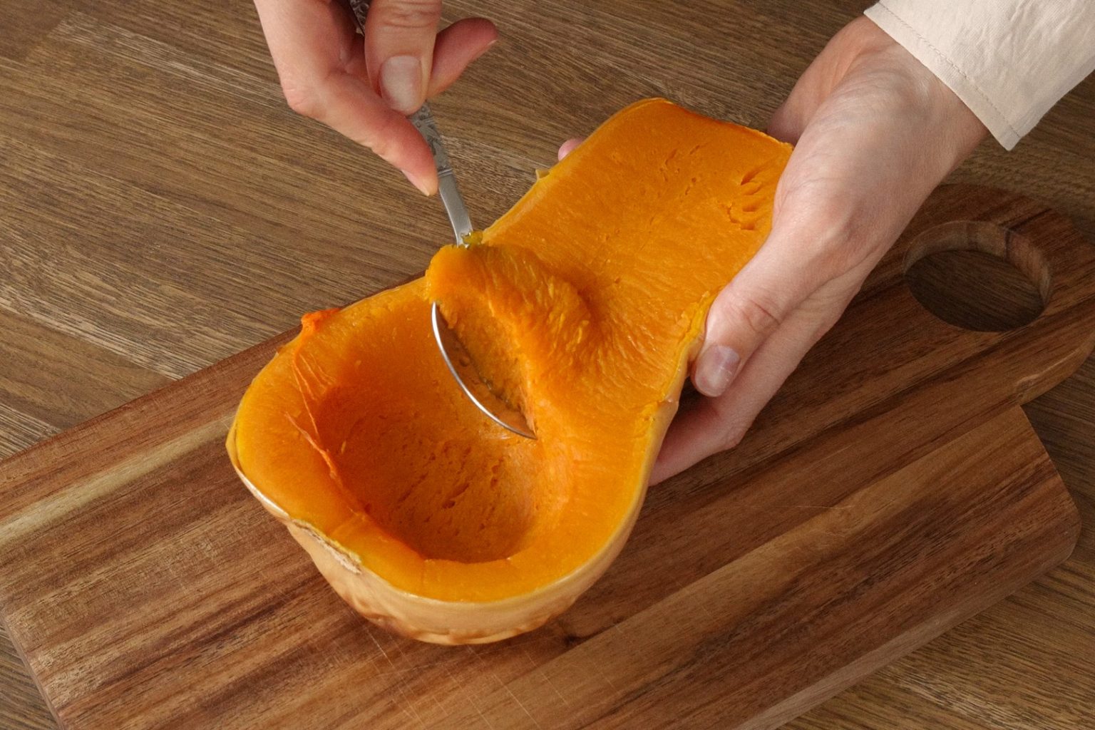 Scooping soft roasted butternut squash with a spoon