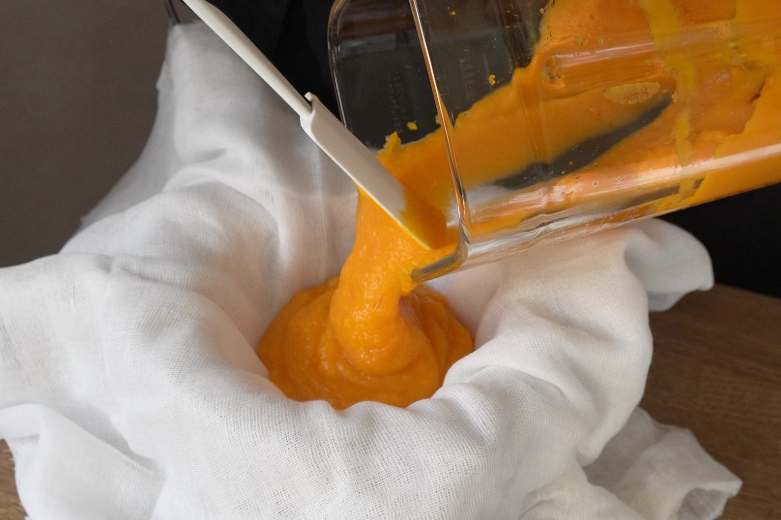 Pouring blended pumpkin puree into a cheesecloth