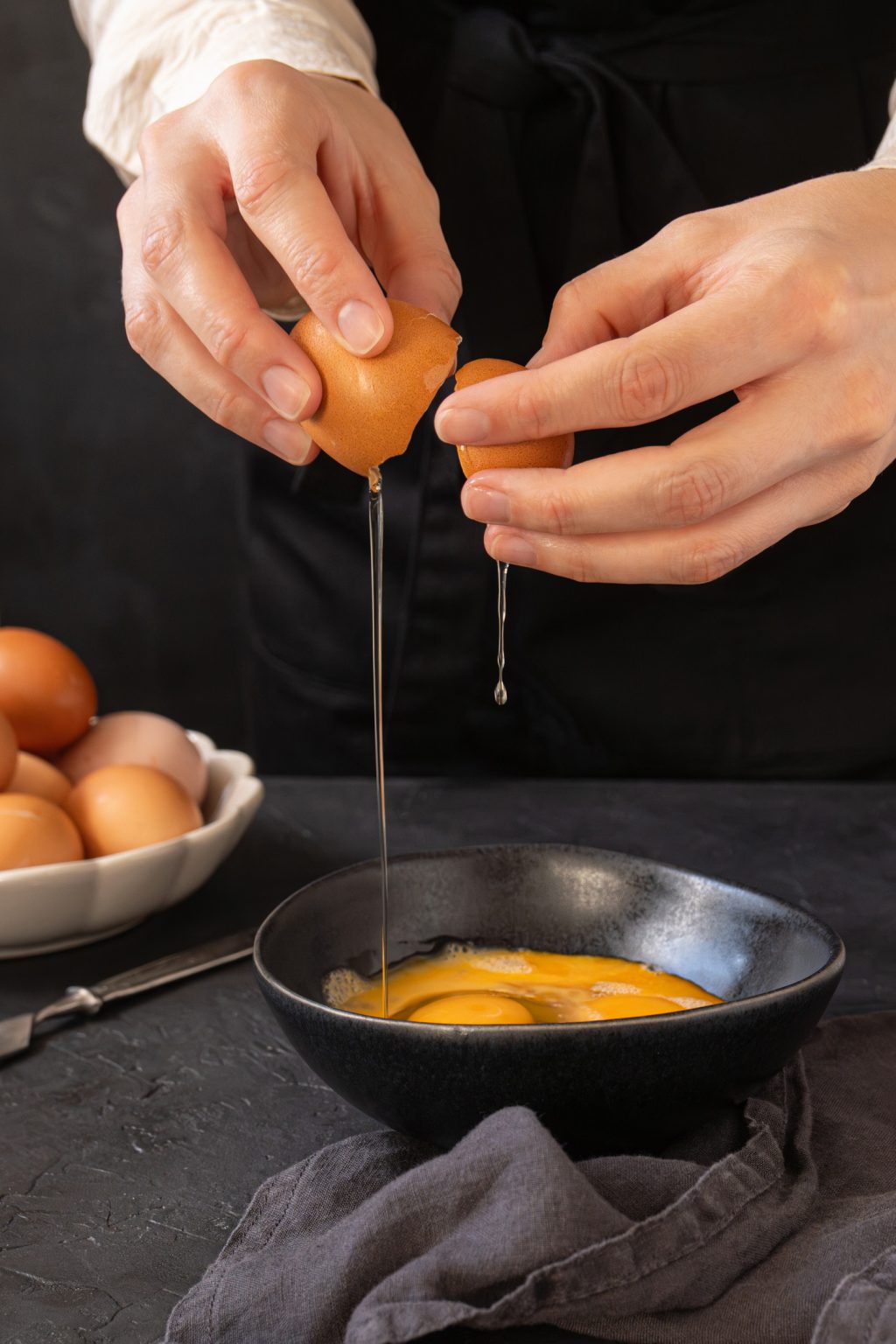 Female hands cracking a raw egg into a bowl for pasteurization