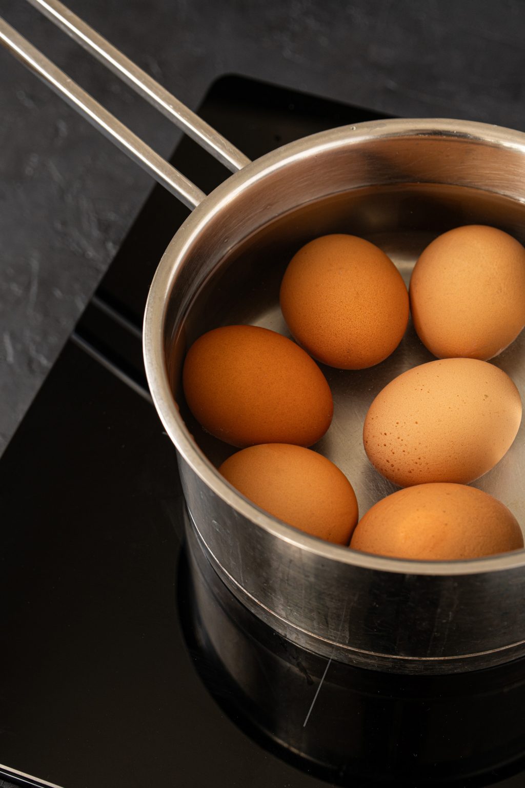 In shell raw eggs placed in a saucepan filled with water