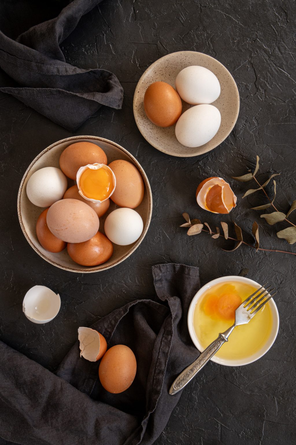 Top view of a bowl full of raw eggs on a dark background
