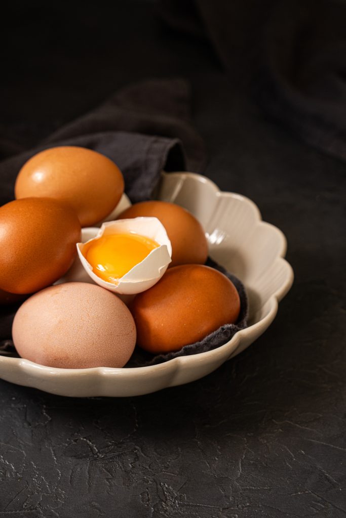Close up of a bowl of raw eggs and a raw egg yolk