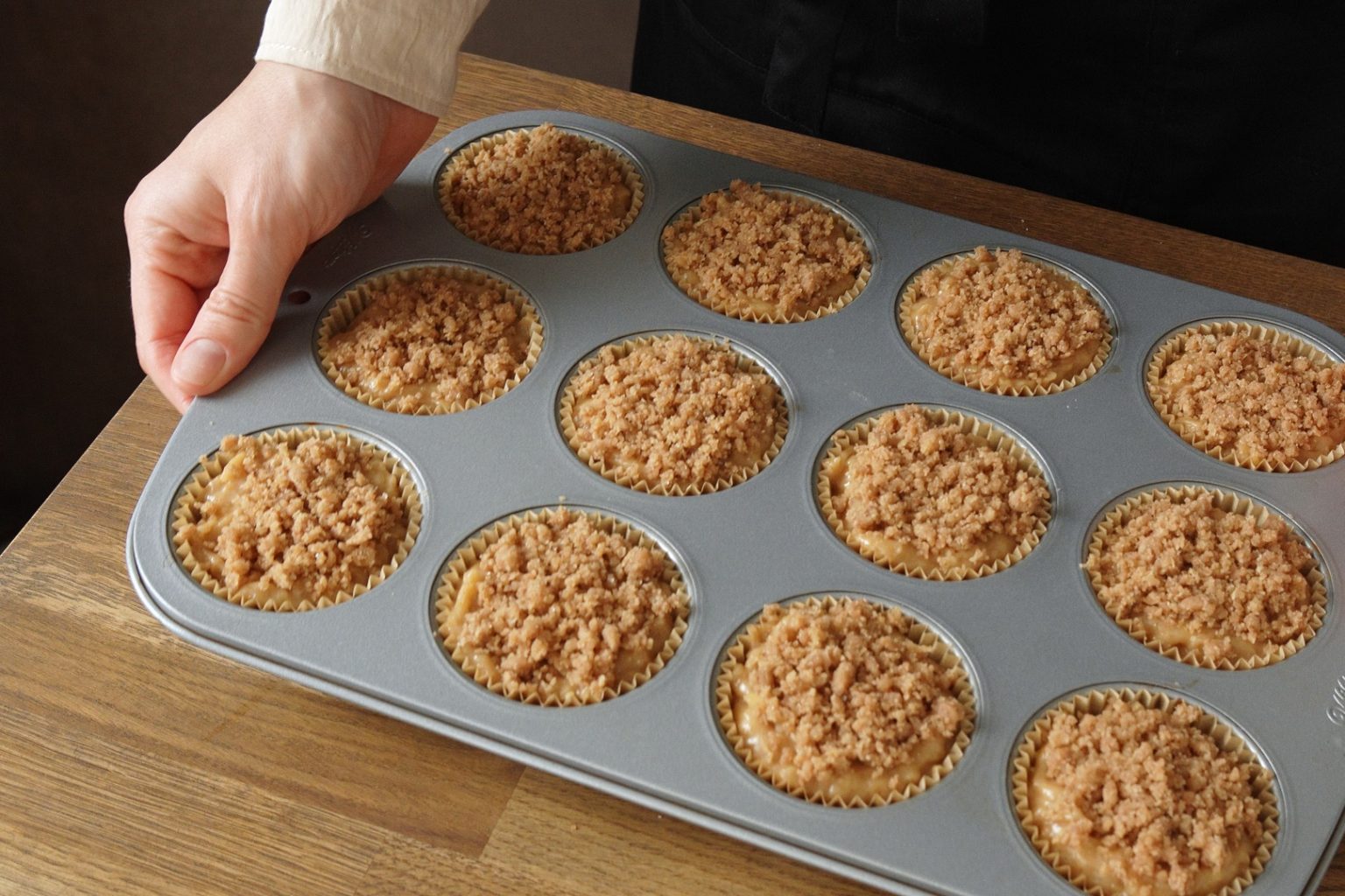 Brown butter apple muffins sprinkled with crumble topping and ready to bake