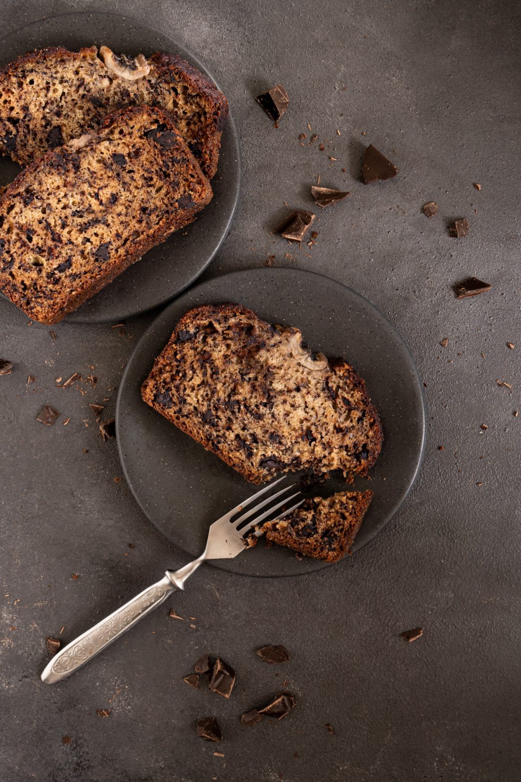 Top view of chocolate chip banana bread slices served on black plates
