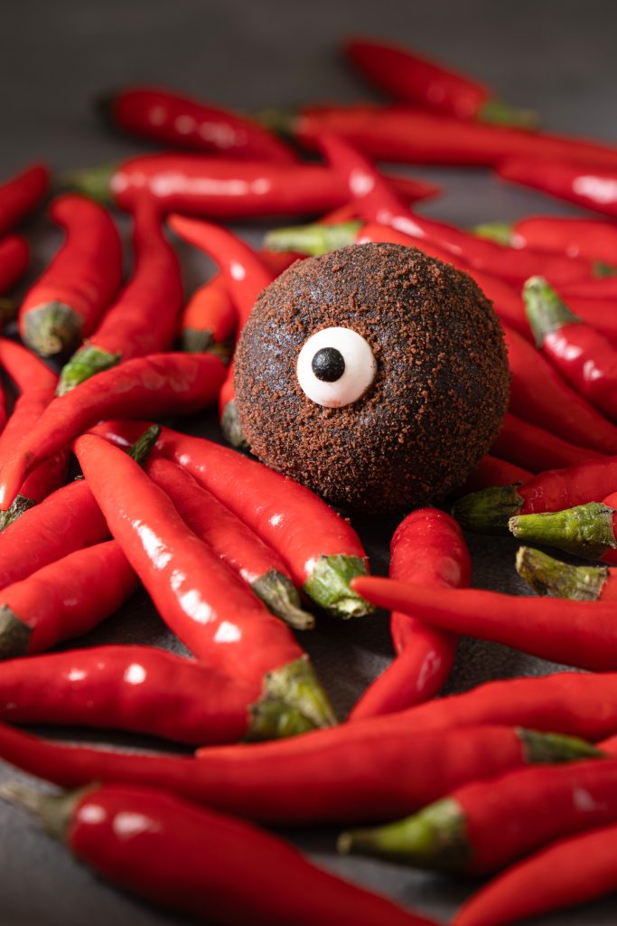 Chocolate Halloween monster truffle on a pile of chili pepper