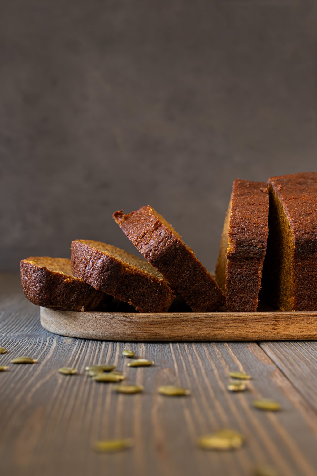 Side view of sliced pumpkin bread served on a wooden tray