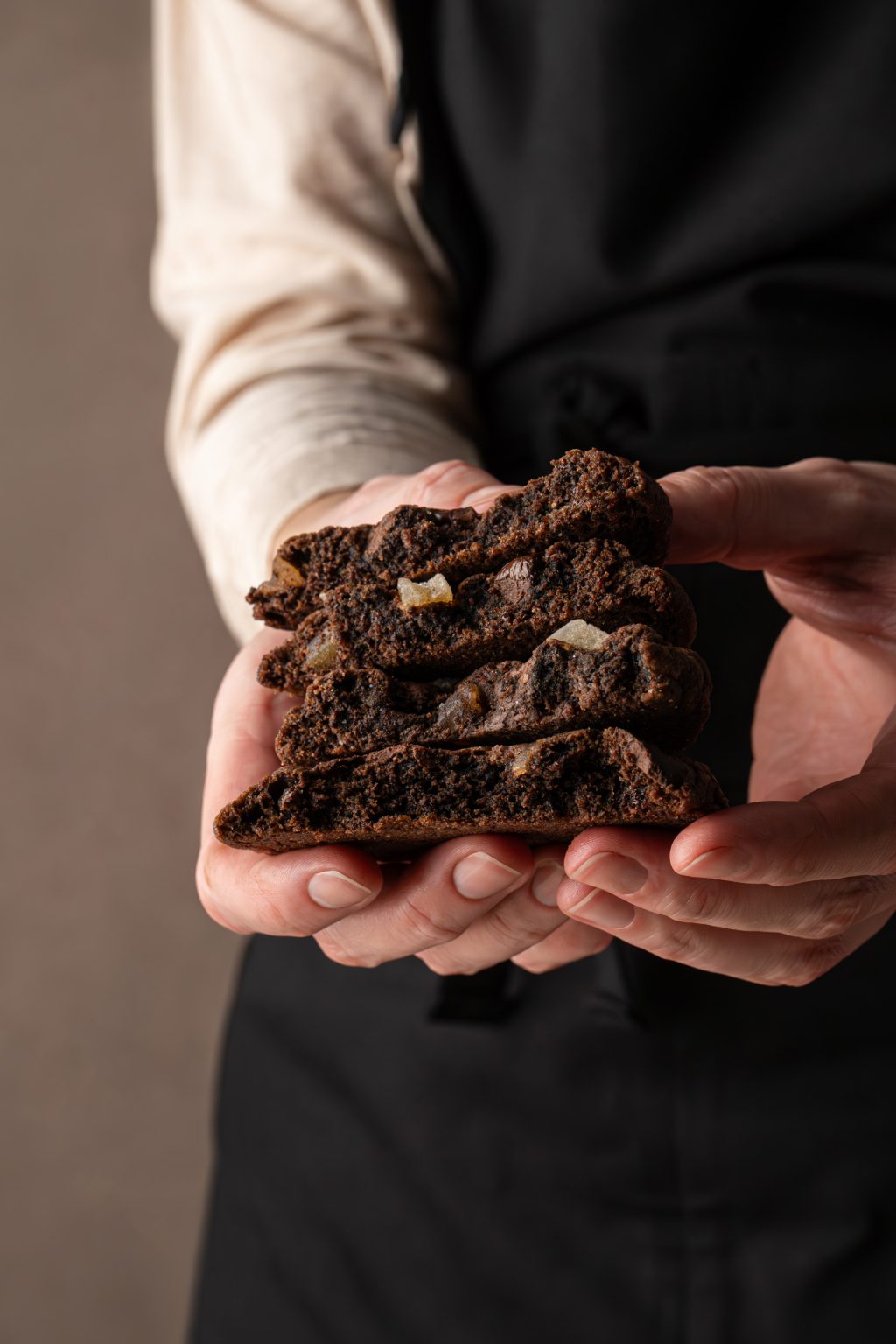 A stack of chocolate ginger cookies held by female hands