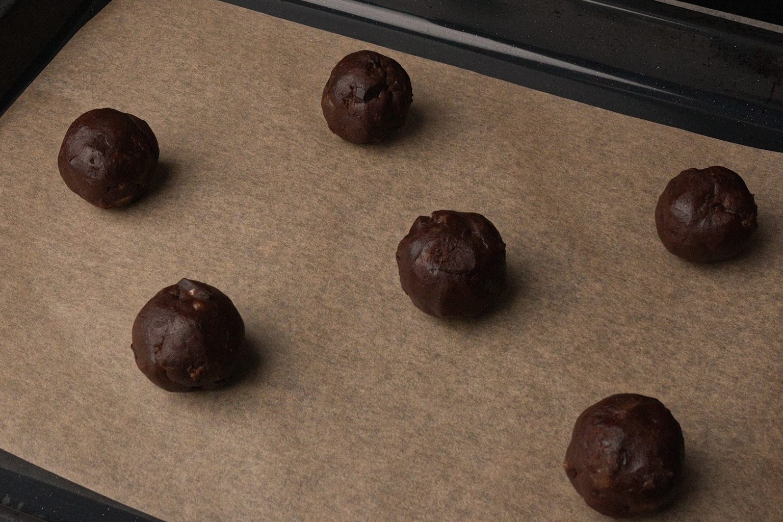 Chocolate ginger cookie dough balls placed on a baking sheet