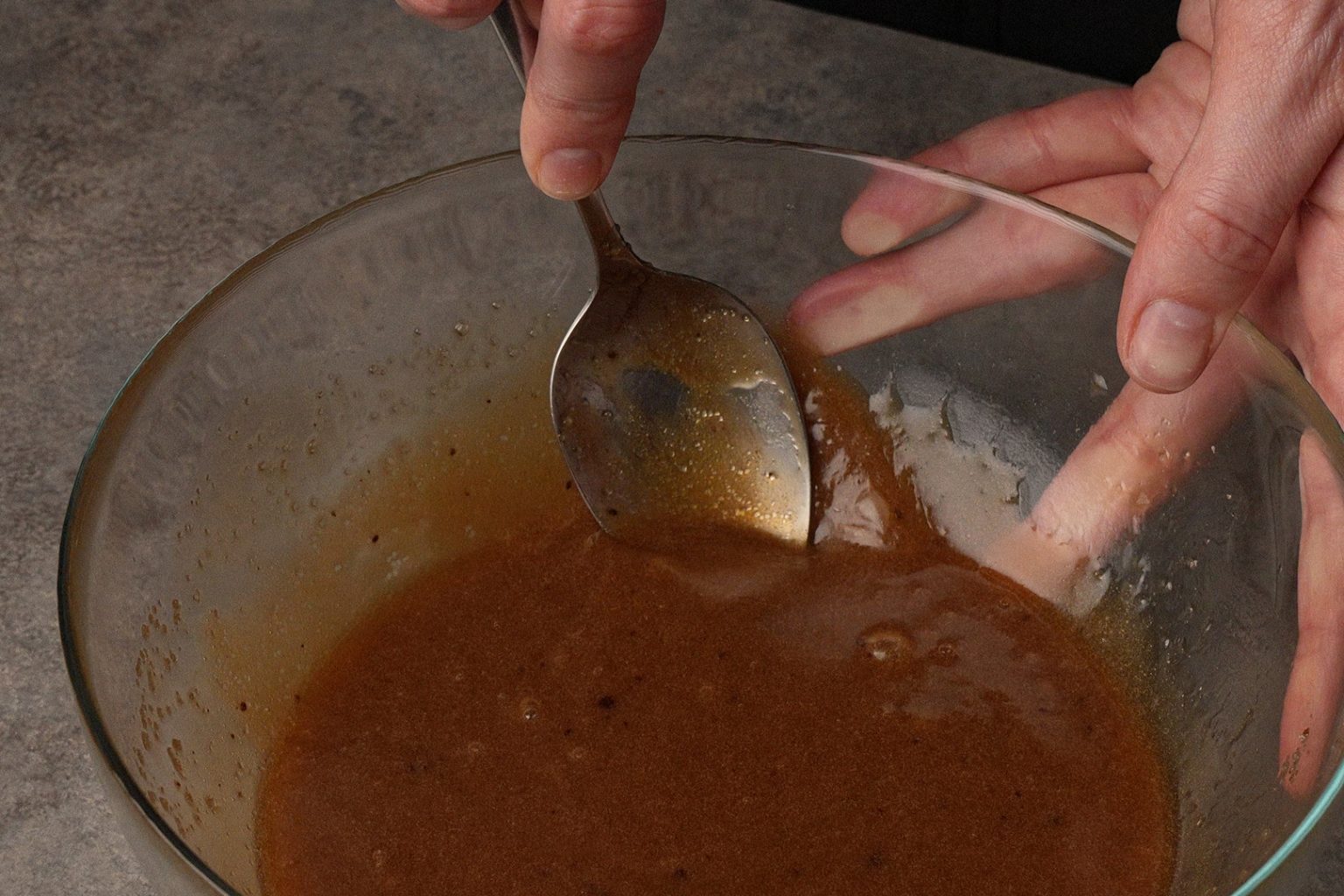 Smashing dark sugar lumps with a spoon