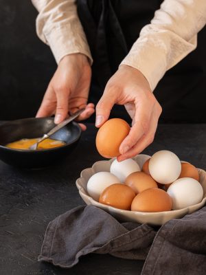 A hand of a female taking a raw egg from the bowl