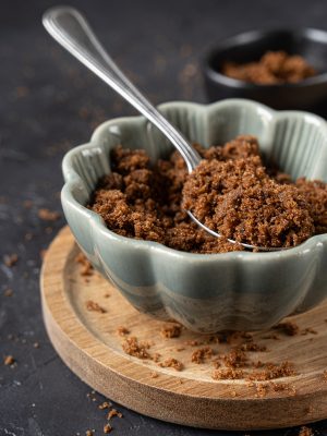 A bowl full of muscovado sugar on a dark background