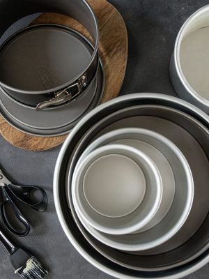 Top view of various cake pans piled on a dark background
